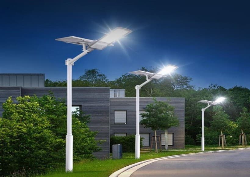 Stalpi de iluminat fotovoltaici, cu becurile aprinse, intr-un cartier de case